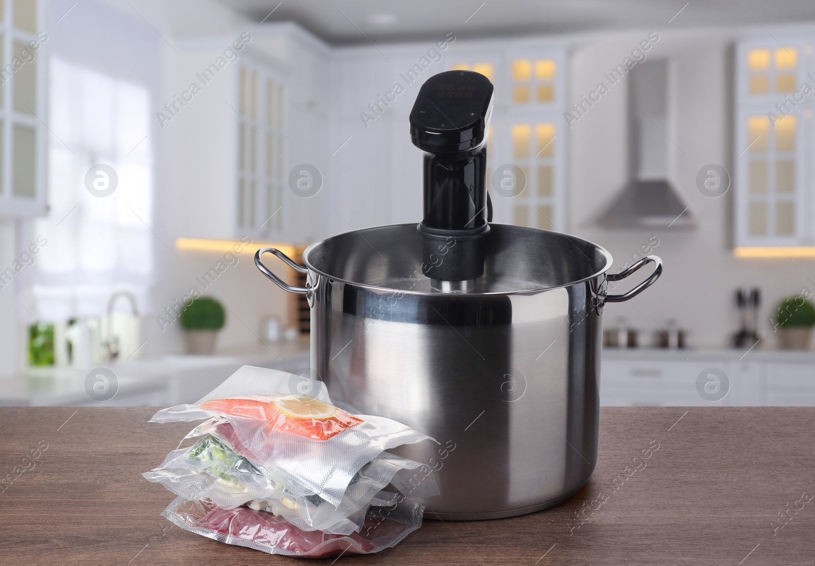 Image of Sous vide cooker in pot and vacuum packed food products on wooden table in kitchen. Thermal immersion circulator