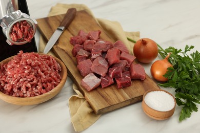 Electric meat grinder with beef and products on white marble table