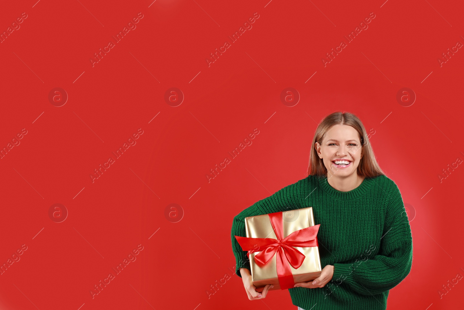 Photo of Happy young woman with Christmas gift on red background. Space for text