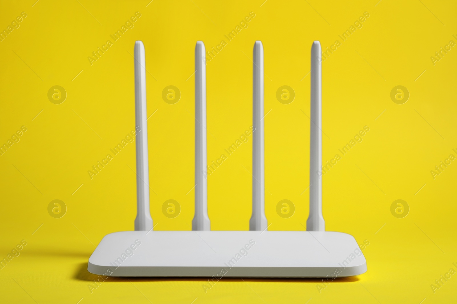 Photo of New white Wi-Fi router on yellow background