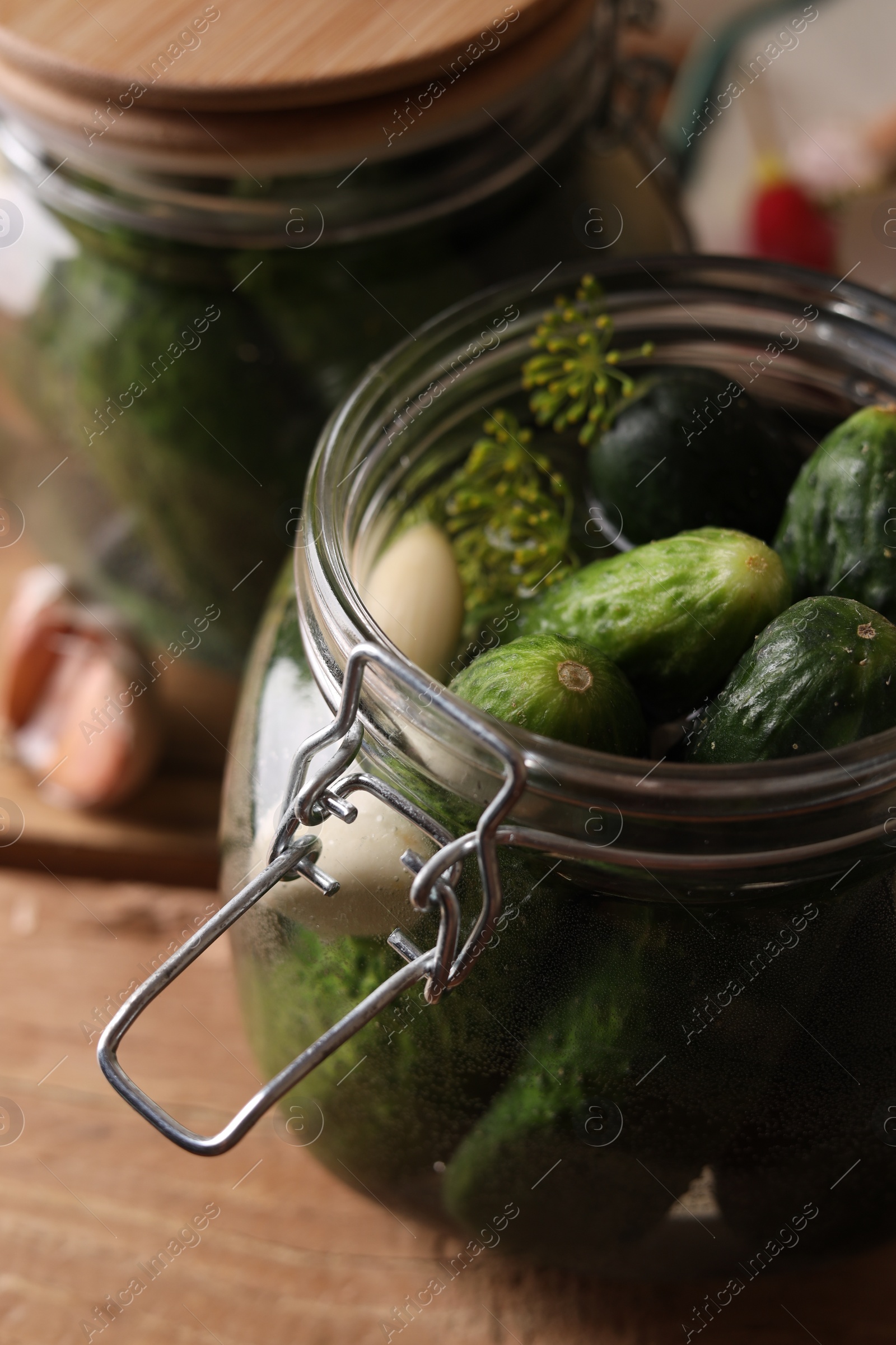 Photo of Jar with cucumbers, garlic and dill on wooden table, closeup. Pickling recipe