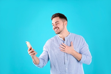 Photo of Man using mobile phone for video chat on color background