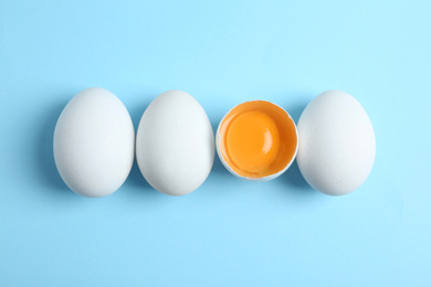 Photo of Fresh raw chicken eggs on light blue background, flat lay