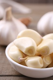 Photo of Aromatic garlic cloves and bulbs on wooden table, closeup