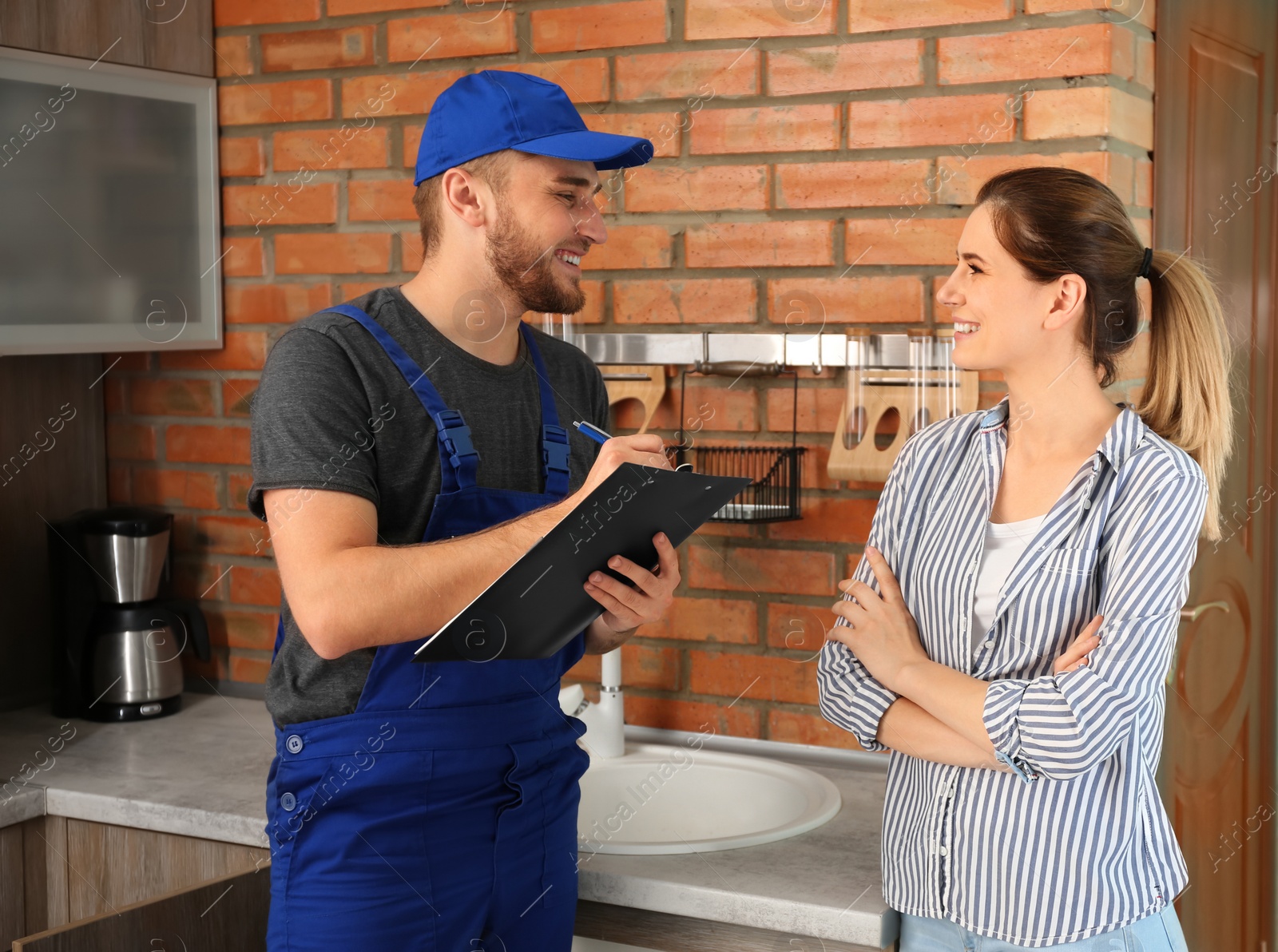 Photo of Professional plumber in uniform with client indoors