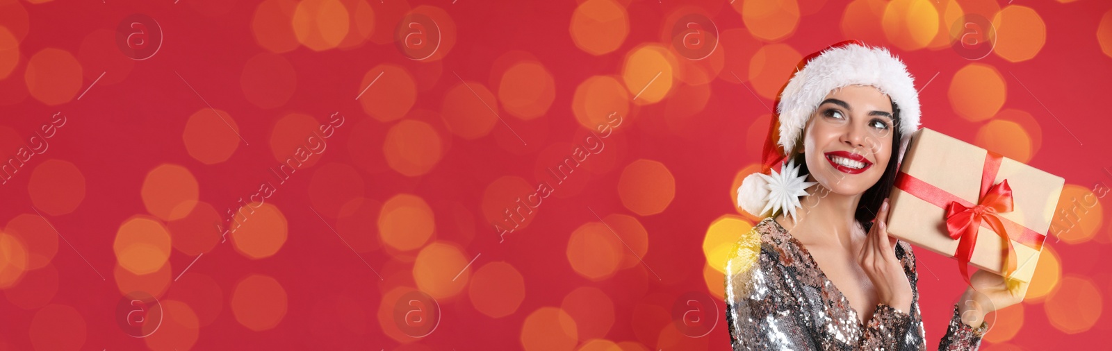 Image of Beautiful woman in Christmas hat holding gift box on red background, space for text. Banner design