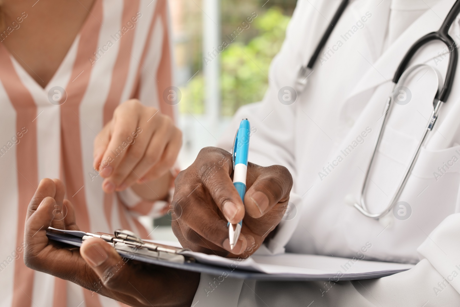 Photo of Young African-American doctor consulting patient in hospital