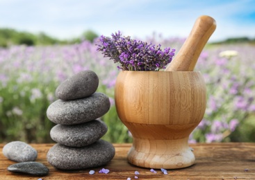 Photo of Spa stones, fresh lavender flowers and mortar on wooden table outdoors, closeup