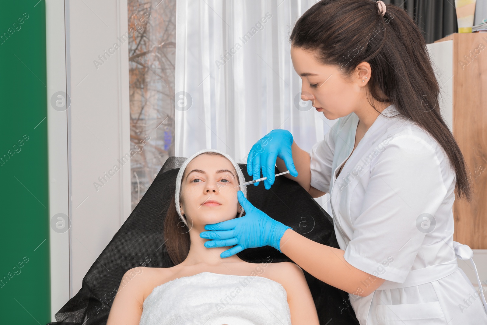 Photo of Cosmetologist giving facial injection to patient in clinic. Cosmetic surgery