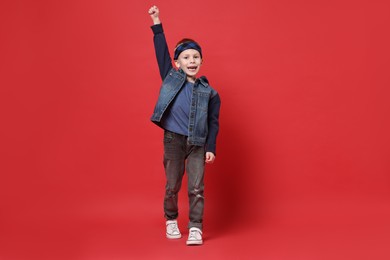 Happy little boy dancing on red background