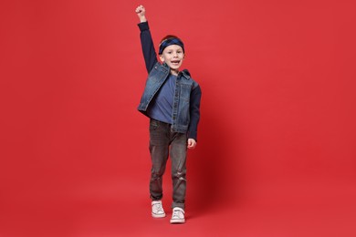 Photo of Happy little boy dancing on red background