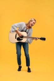 Happy hippie woman playing guitar on yellow background
