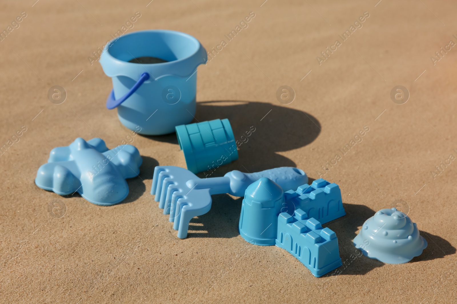 Photo of Set of plastic beach toys on sand. Outdoor play