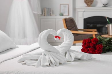 Honeymoon. Swans made of towels and beautiful red roses on bed in room