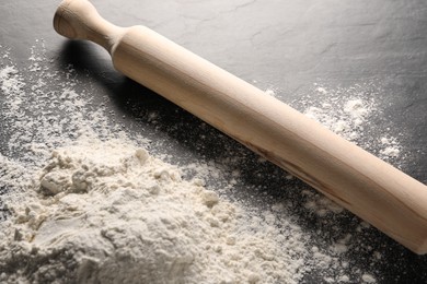 Photo of Pile of flour and rolling pin on grey textured table, closeup