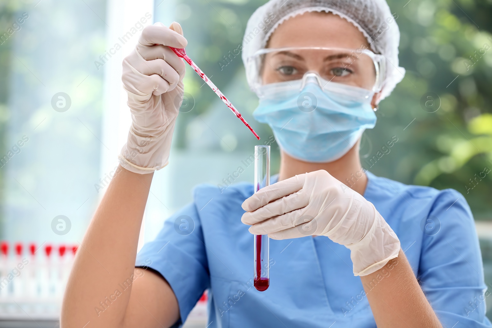 Photo of Scientist dripping blood into test tube in laboratory