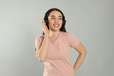 Photo of Happy woman in headphones listening music on grey background
