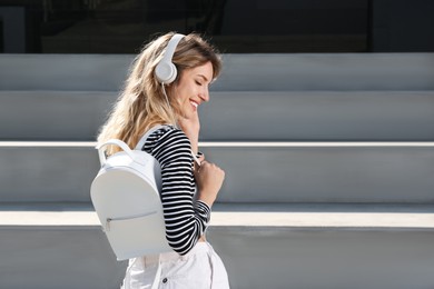 Young woman with stylish backpack on stairs outdoors. Space for text