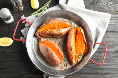 Photo of Flat lay composition with baked sweet potatoes in dish on wooden background