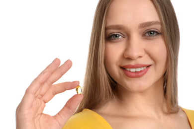 Young woman with vitamin capsule on white background