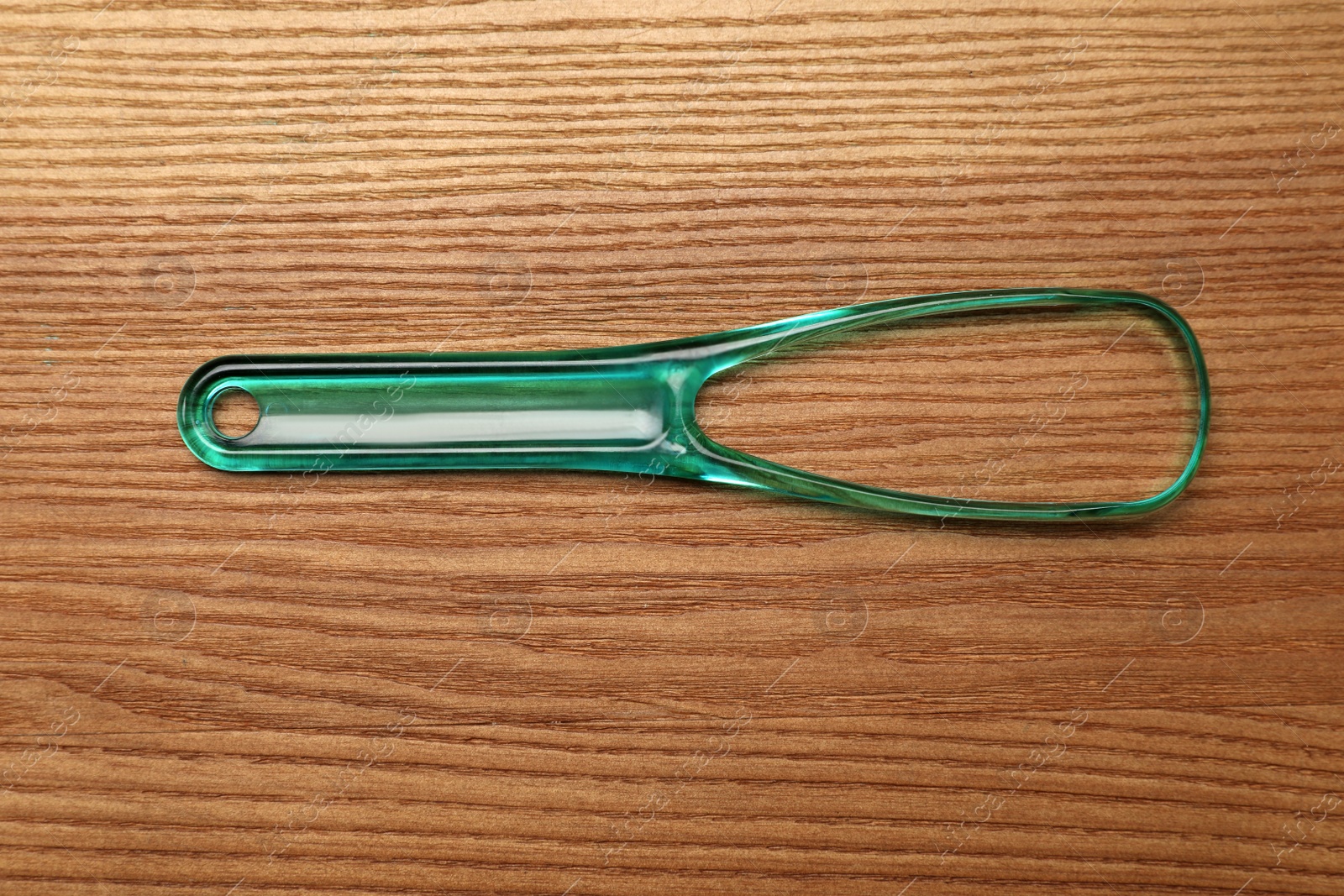 Photo of Green tongue cleaner on wooden table, top view