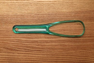 Green tongue cleaner on wooden table, top view