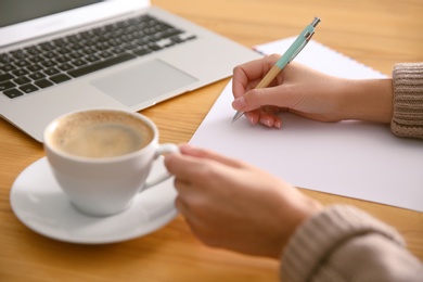 Woman writing letter at wooden table, closeup