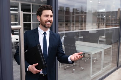 Male real estate agent with leather portfolio inviting inside