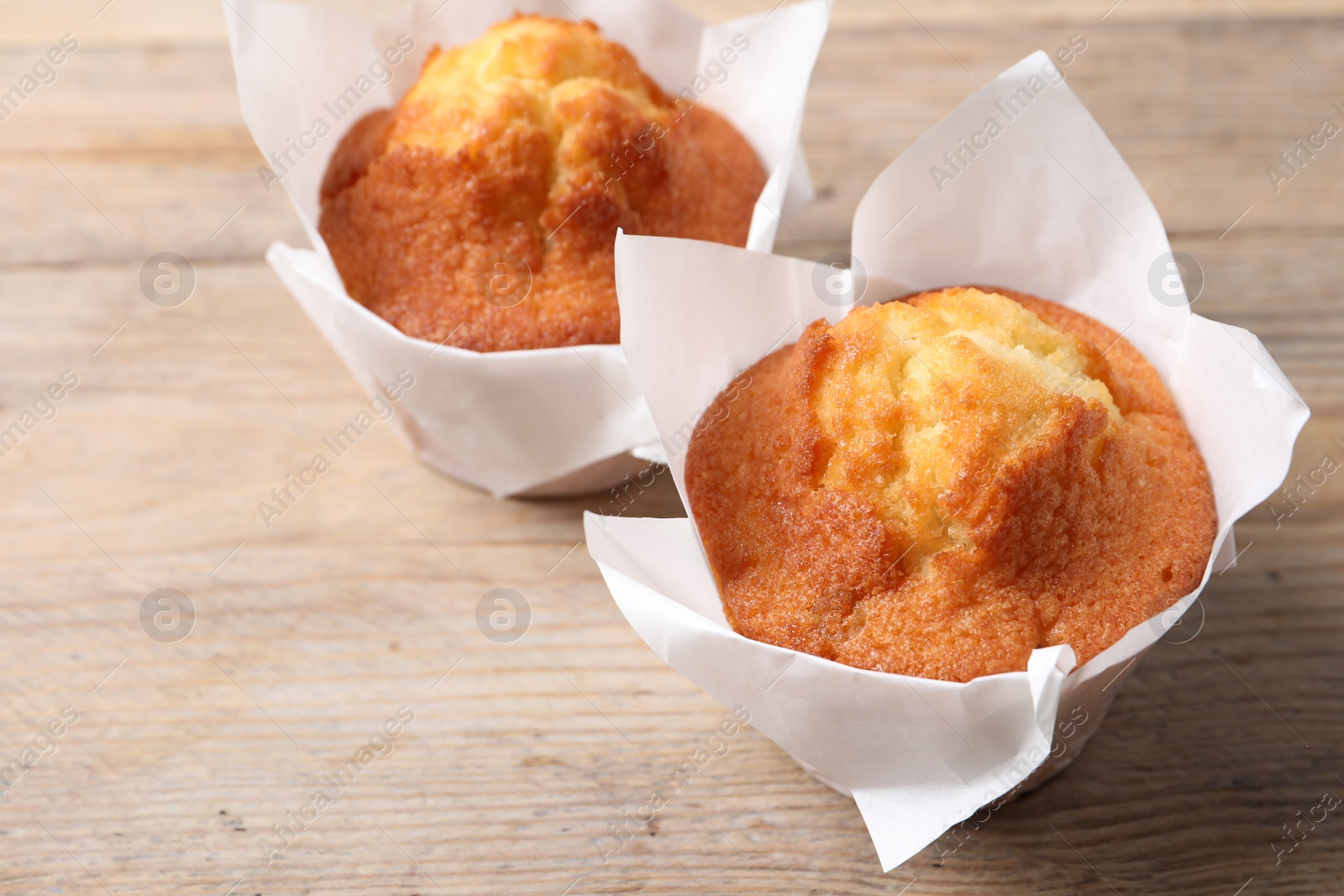 Photo of Delicious sweet muffins on wooden table, closeup. Space for text