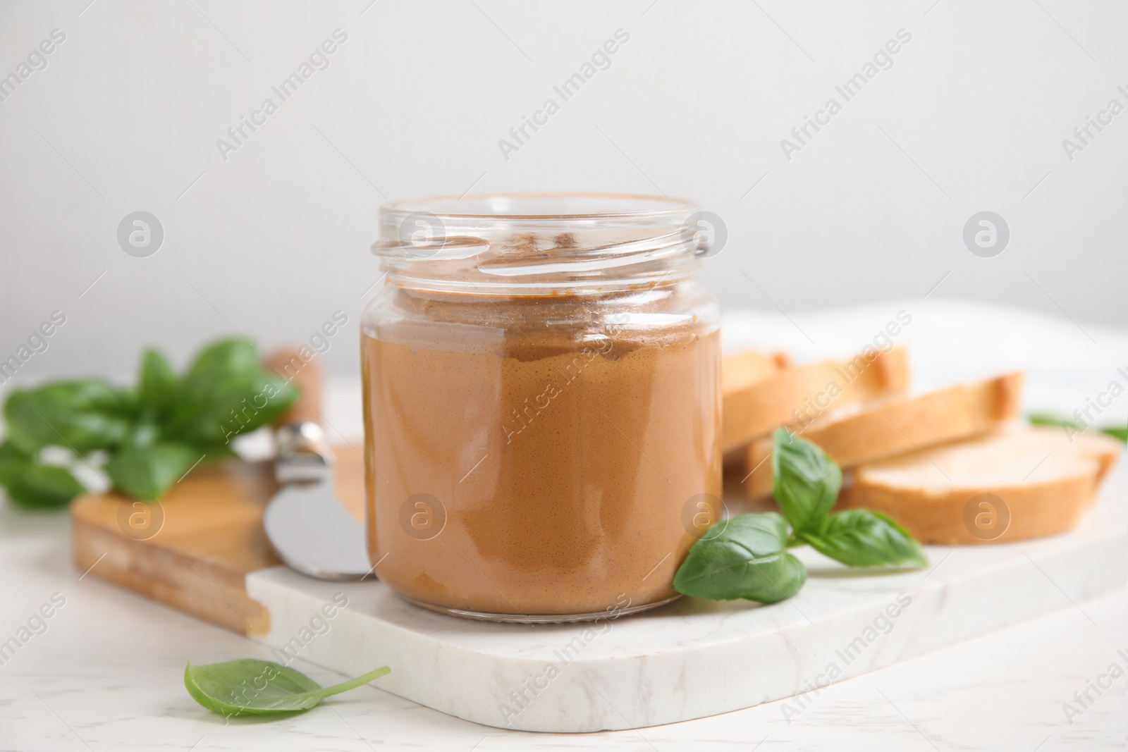 Photo of Delicious meat pate, fresh bread and basil on white wooden table