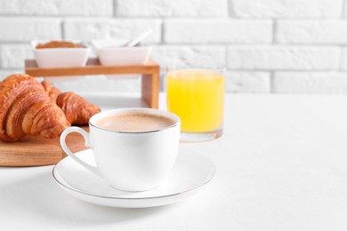 Breakfast time. Fresh croissants and coffee on white table. Space for text