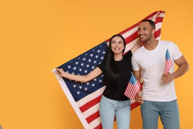 Photo of 4th of July - Independence Day of USA. Happy couple with American flags on yellow background, space for text