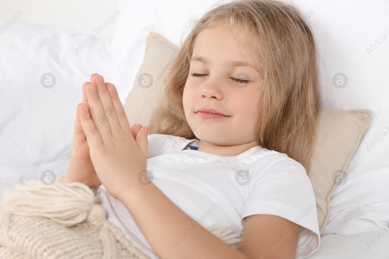 Photo of Girl with clasped hands praying in bed