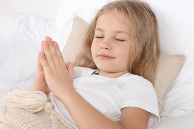 Photo of Girl with clasped hands praying in bed