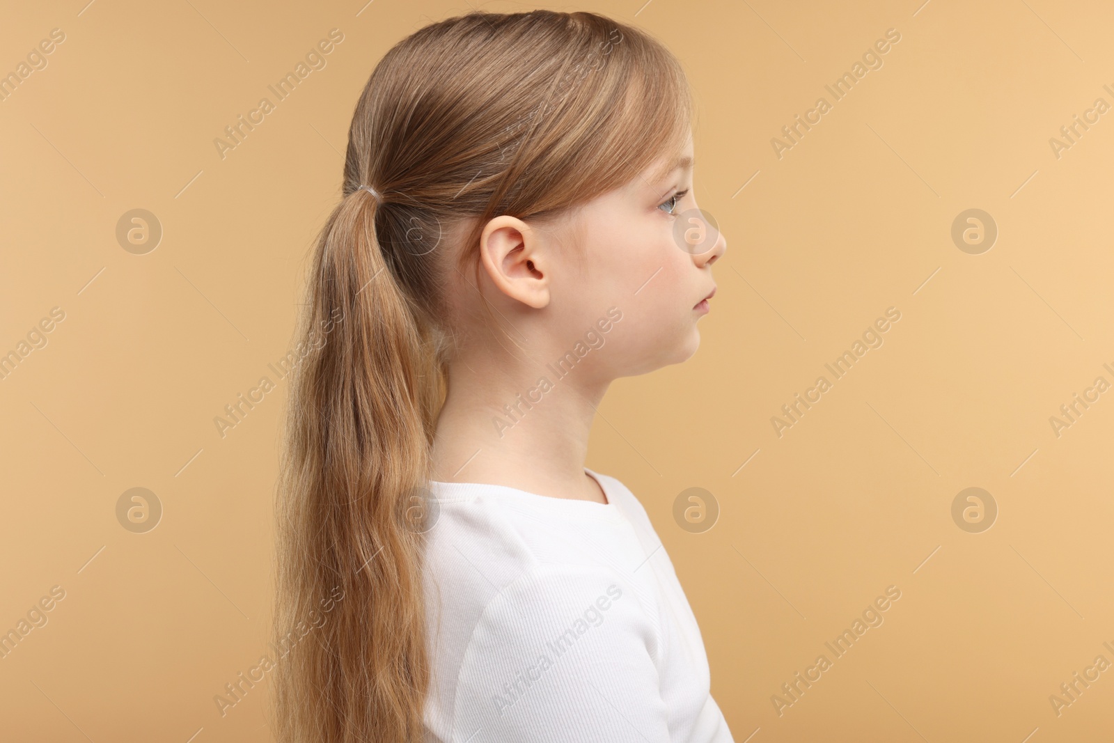 Photo of Hearing problem. Little girl on pale brown background