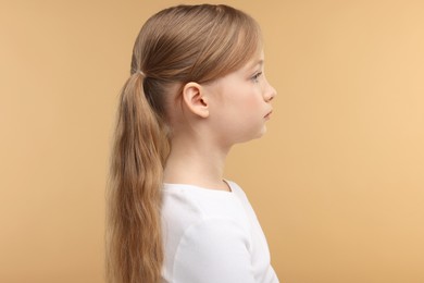 Photo of Hearing problem. Little girl on pale brown background