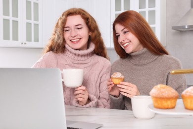 Photo of Beautiful young sisters spending time together in kitchen