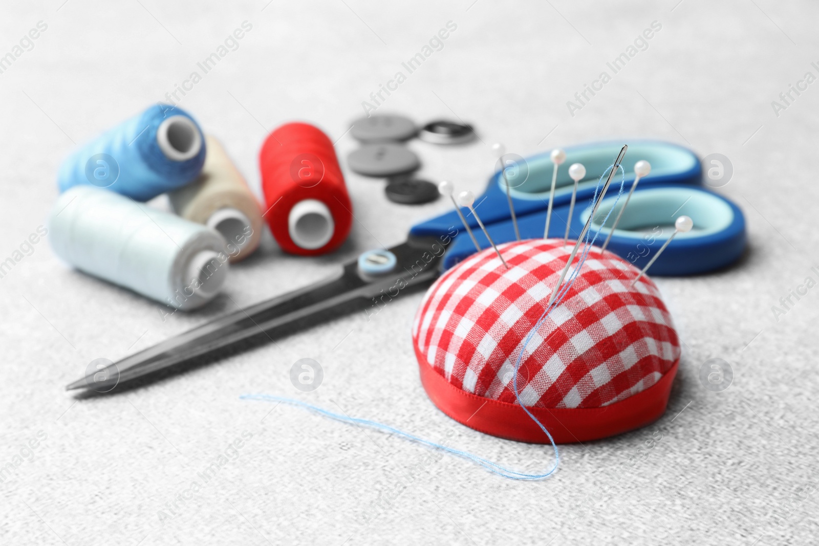 Photo of Pincushion, spools of threads, buttons and scissors on white background
