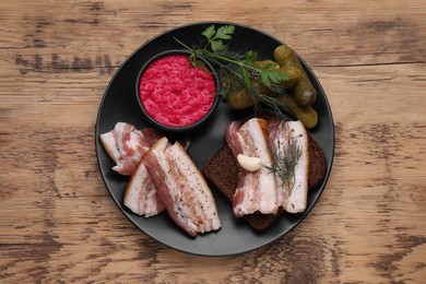 Photo of Pork fatback with rye bread and ingredients on wooden table, top view