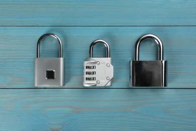 Photo of Different padlocks on light blue wooden table, flat lay
