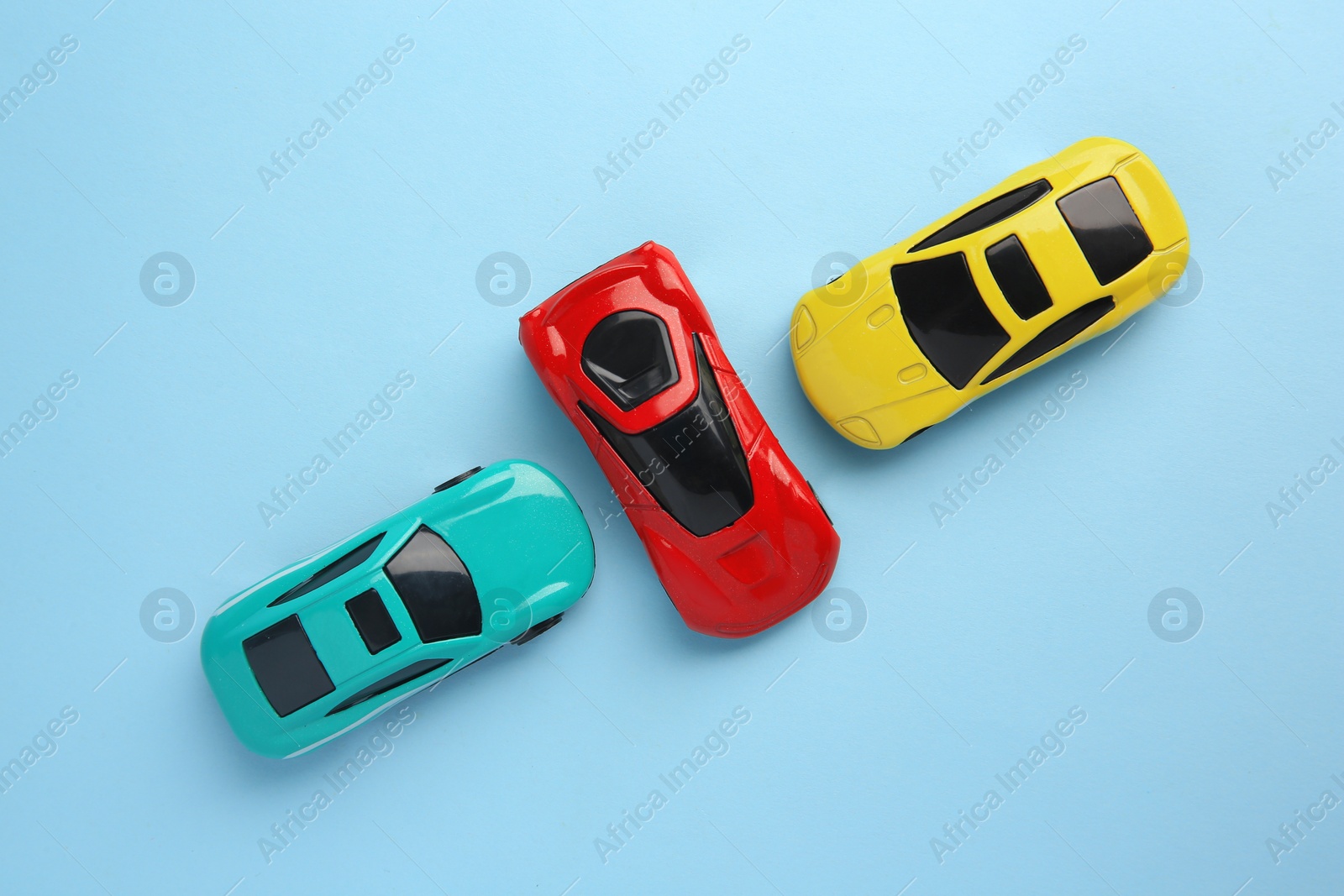 Photo of Different bright cars on light blue background, flat lay. Children`s toys