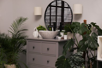 Photo of Stylish bathroom interior with modern furniture and beautiful green houseplants