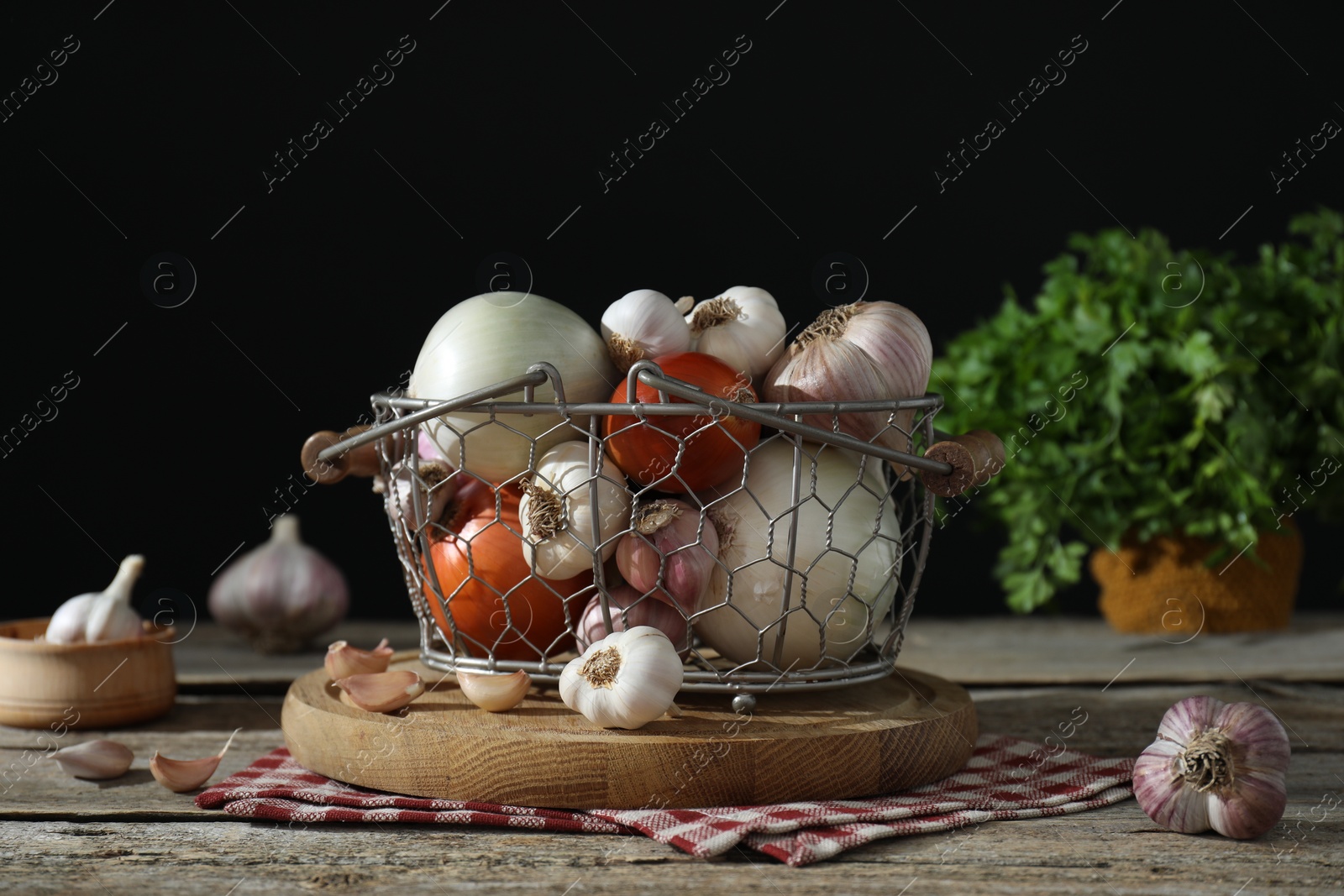 Photo of Fresh raw garlic and onions in metal basket on table