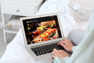 Woman using laptop for ordering food online at home, closeup. Concept of delivery service