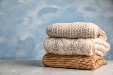 Photo of Stack of folded knitted sweaters on table. Space for text