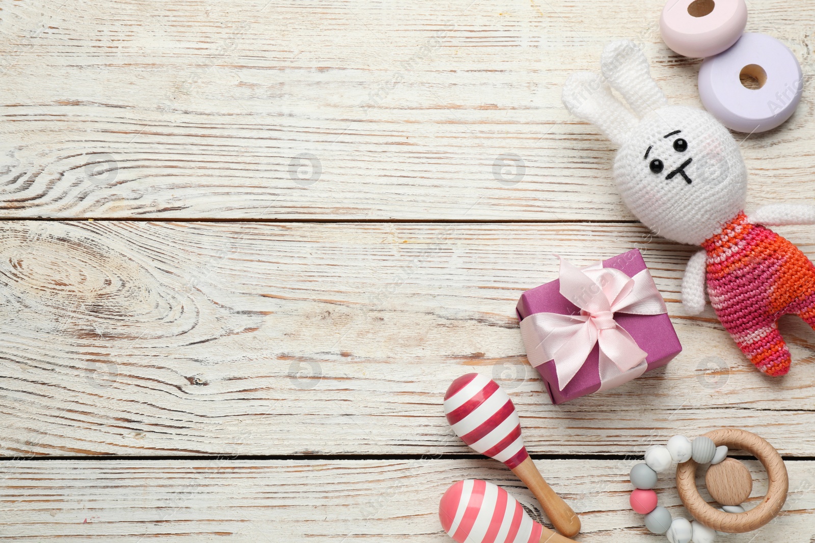 Photo of Cute baby toys and gift box on white wooden background, flat lay. Space for text