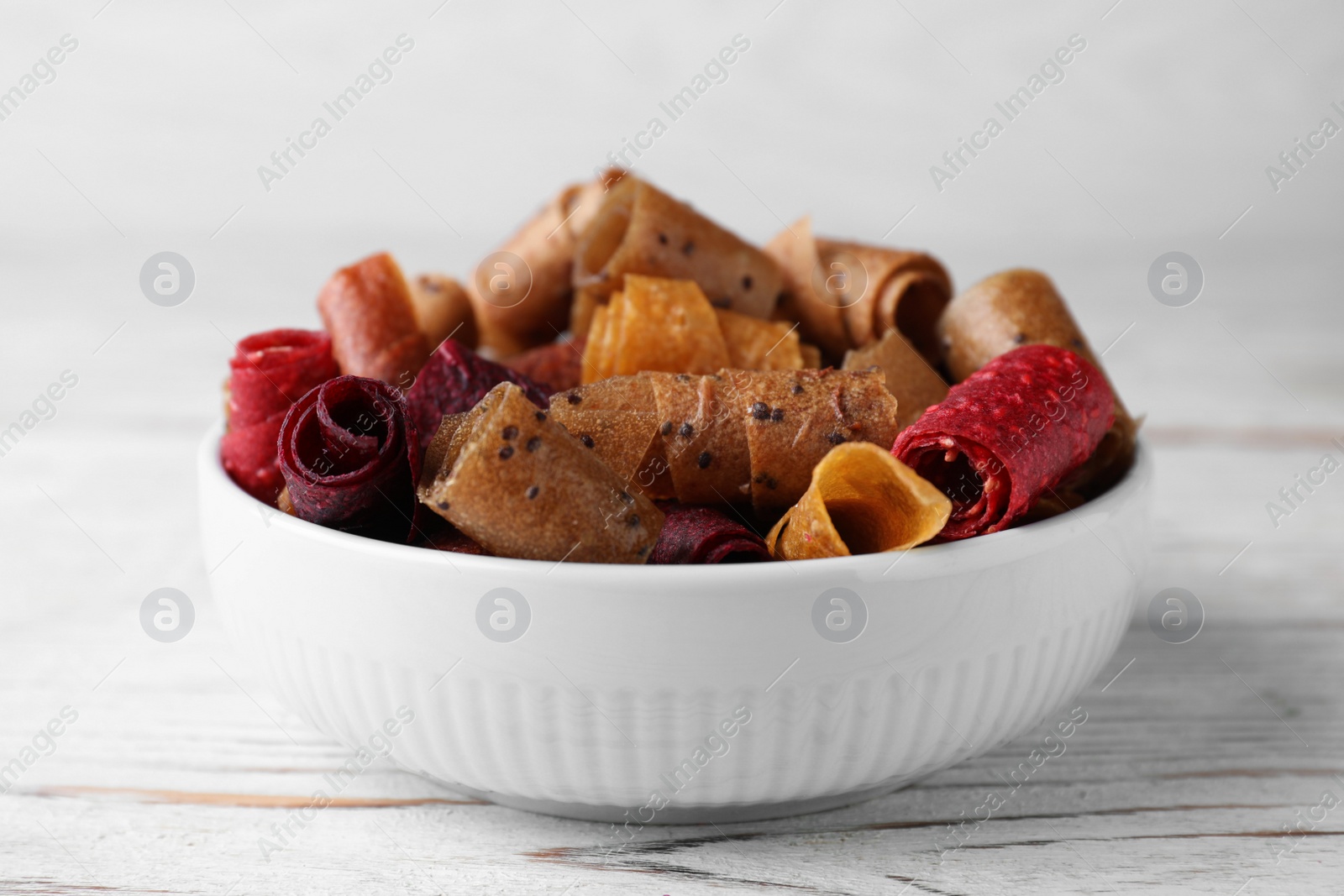 Photo of Delicious fruit leather rolls on white wooden table