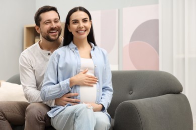 Happy pregnant woman with her husband on sofa at home