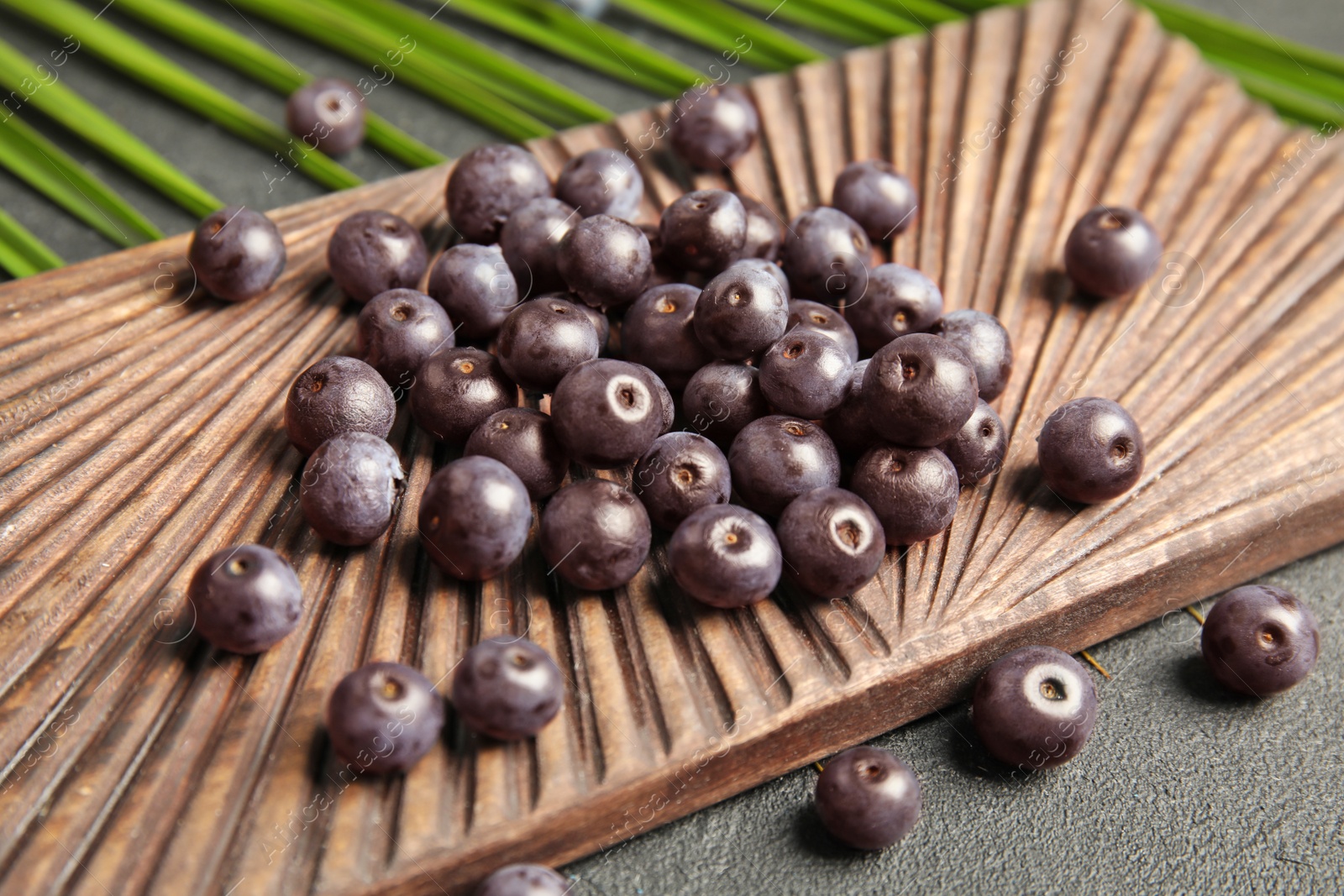 Photo of Fresh acai berries on wooden board, closeup