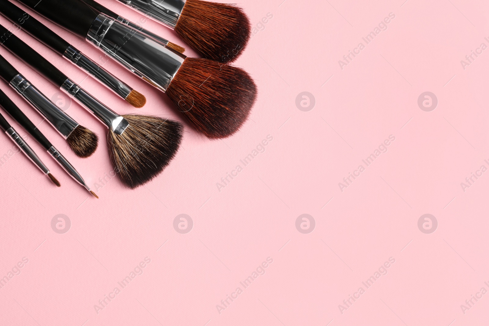 Photo of Different makeup brushes on pink background, flat lay. Space for text